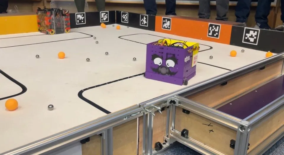 A purple box robot with a cartoon face in the Unibots UK arena