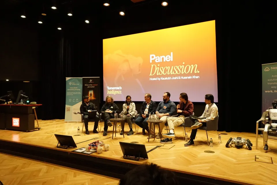 Panellists seated on stage beneath a large “Panel Discussion” slide at Tomorrow’s Intelligence