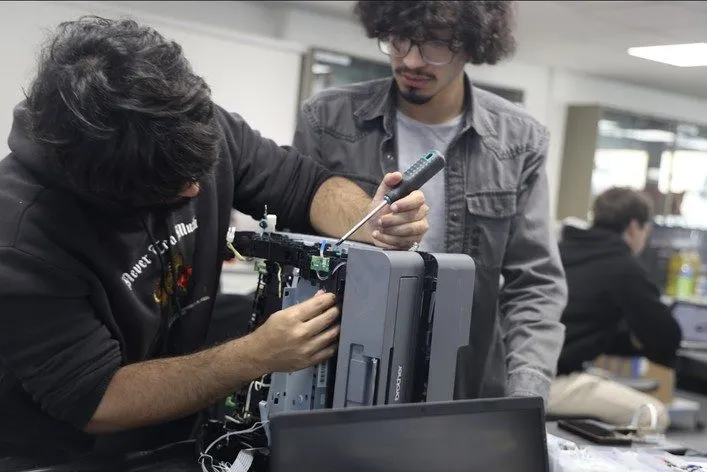 A hacker drives a screwdriver into a printer chassis