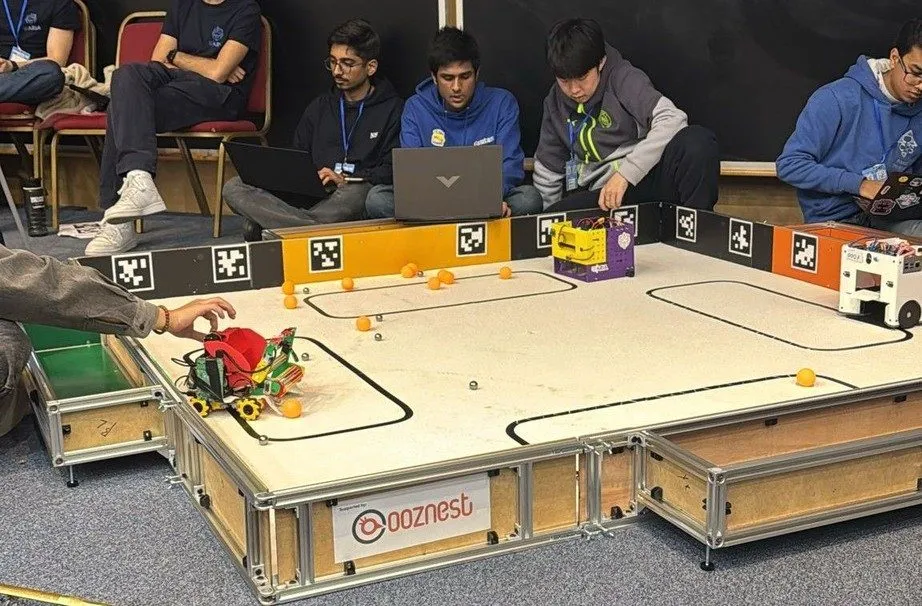 Teams crowd around the Unibots UK competition arena